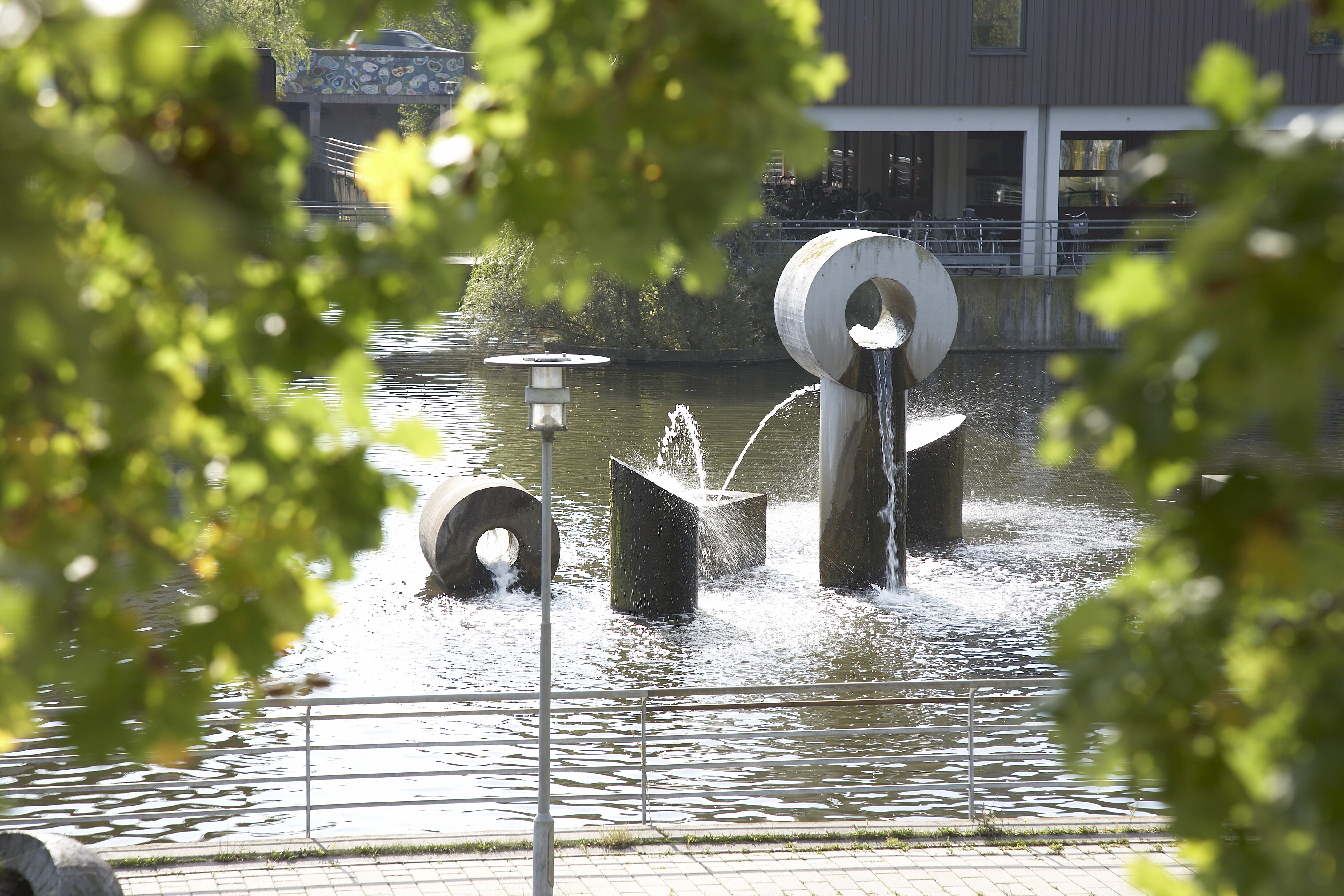 Albertslund Rådhus med rådhussøen og træer i forgrunden.