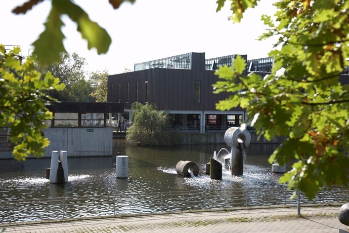 Albertslund Rådhus med rådhussøen og træer i forgrunden.